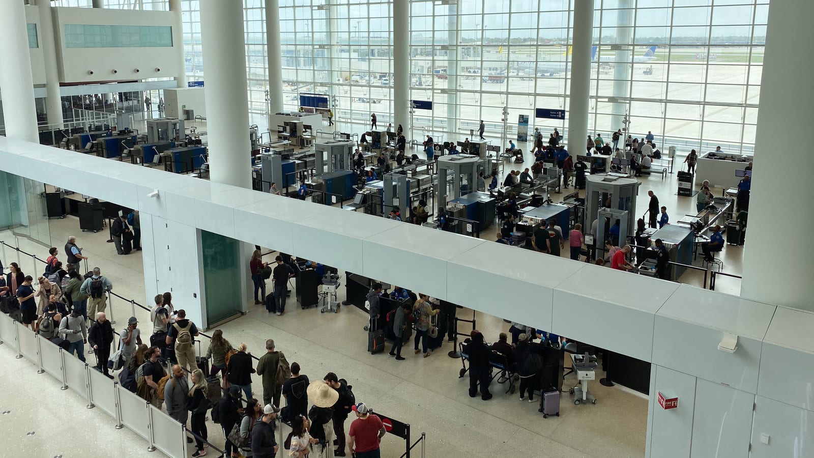 Travellers queuing with cabin luggage at an airport security checkpoint, where medication rules are enforced