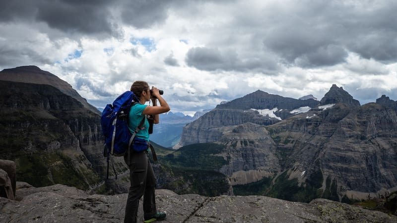 Hiker with a backpack looking out over a mountain range, the kind of trip travel insurance has to cover