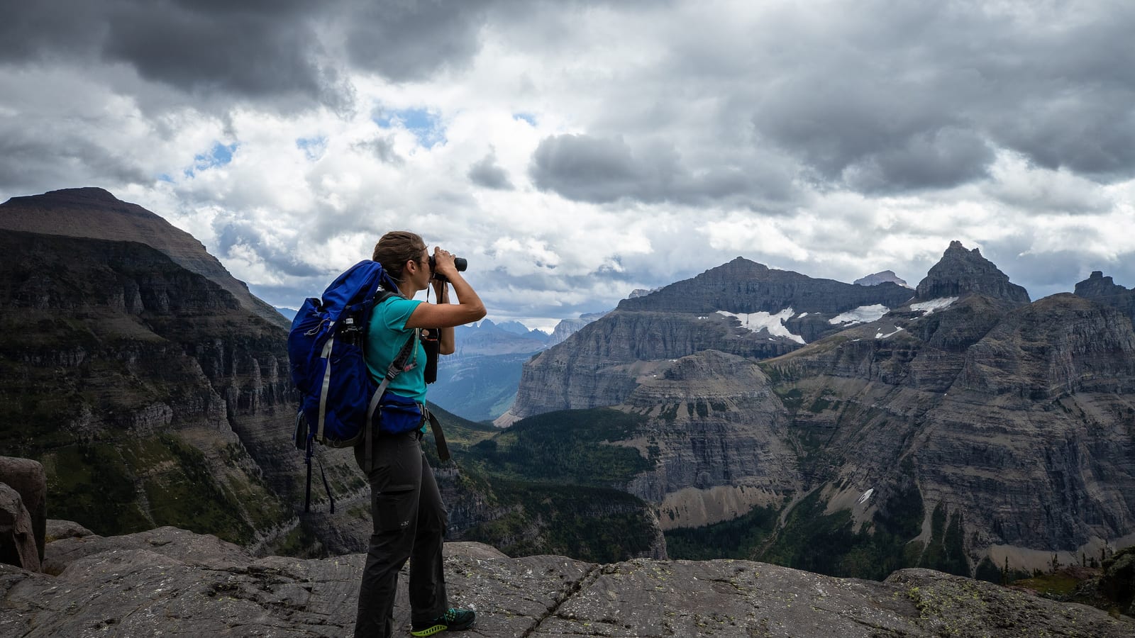 Hiker with a backpack looking out over a mountain range, the kind of trip travel insurance has to cover