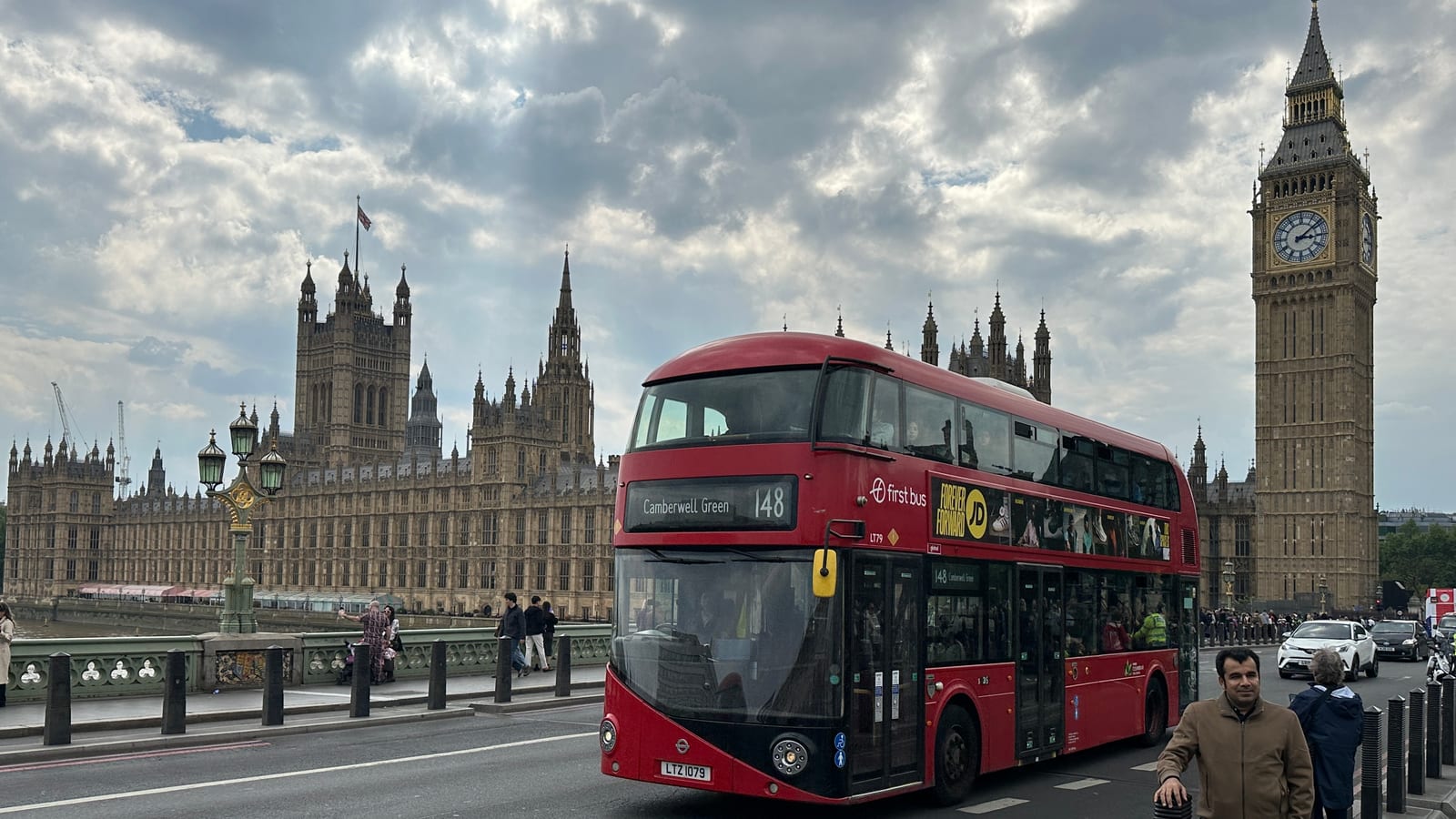 A red London bus crossing Westminster Bridge with the Palace of Westminster and Big Ben behind